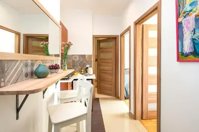 a kitchen with a wooden table and white chairs at Blue Sky Apartment in Kraków