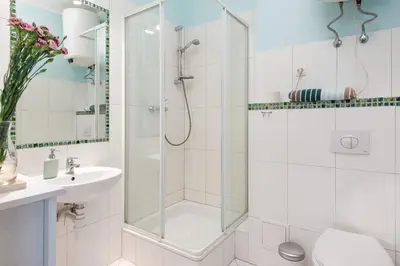 a white bathroom with a shower and a sink at Blue Sky Apartment in Kraków