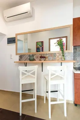 a kitchen with two white stools and a counter at Blue Sky Apartment in Kraków