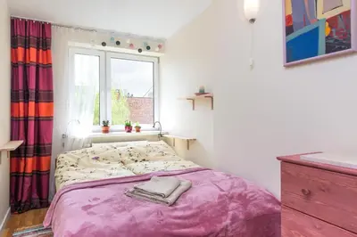 a bedroom with a bed with a purple blanket and a window at Blue Sky Apartment in Kraków
