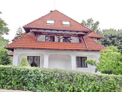 a white house with a red roof on top of a hedge at VILLA CASSIA przy Parku Zdrojowym in Rabka