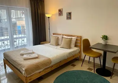 a bedroom with a bed and a table and a window at Bubble Apartments in Kraków