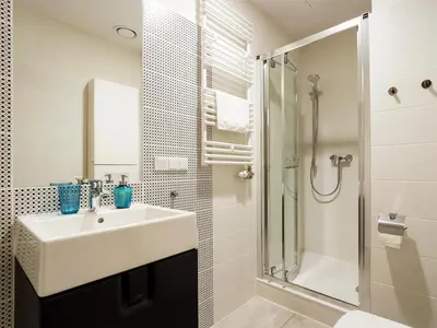 a white bathroom with a sink and a shower at Riverside Aparthotel Cracow in Kraków
