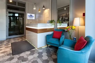 a bathroom with two blue chairs and a tub at Riverside Aparthotel Cracow in Kraków