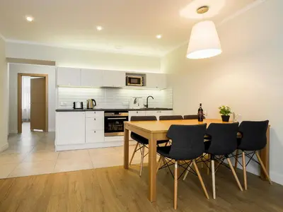 a kitchen with a wooden table and black chairs at Riverside Aparthotel Cracow in Kraków