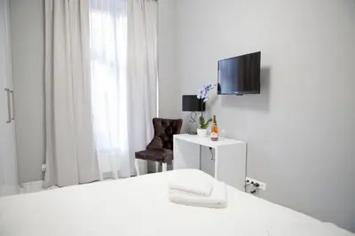 a white room with a bed and a tv at Elegant City Center Zyblikiewicza 14 in Kraków