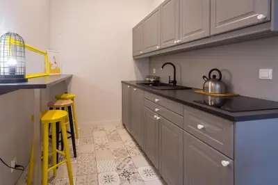 a kitchen with gray cabinets and yellow stools in it at Between Old Town and Kazimierz in Kraków