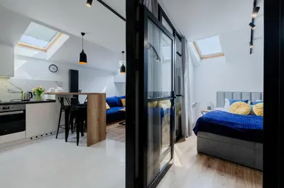 a room with a bed and a kitchen with a table at Downtown Apartments Cracow in Kraków