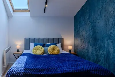 a bedroom with a blue bed with two yellow pillows at Downtown Apartments Cracow in Kraków