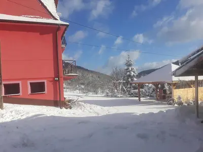 a red building with snow on the ground at Malinowy Domek in Młyńczyska