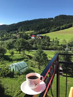 a cup of coffee sitting on top of a balcony at Malinowy Domek in Młyńczyska