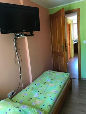 a bedroom with a bed with a flat screen tv on the wall at Malinowy Domek in Młyńczyska