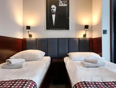 two twin beds in a hotel room with a picture on the wall at Atlantic Aparthotel in Kraków