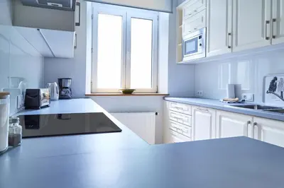 a white kitchen with white cabinets and a window at Kraków Old Town 2 bedroom royal apartment in Kraków