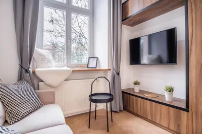 a living room with a tv and a chair at MB Cracow Apartments in Kraków