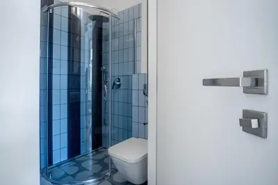 a bathroom with a toilet and a shower with blue tiles at MB Cracow Apartments in Kraków