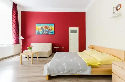 a bedroom with a red accent wall and a bed at Fantasia Apartments in Kraków