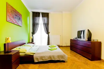 a bedroom with green walls and a bed and a tv at Fantasia Apartments in Kraków