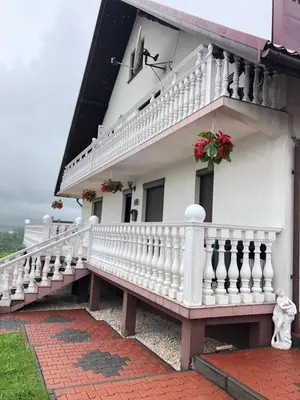 a white building with a white balcony and flowers at Grand Panorama in Wiśniowa