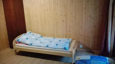 a small bed in a room with a wooden wall at Agroturystyka pod Pstragiem in Zawoja