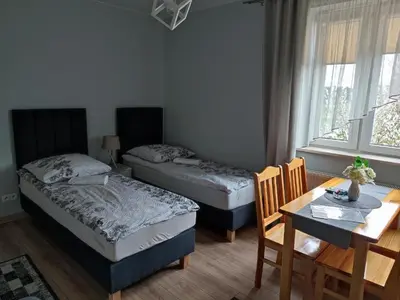 a room with two beds and a table and a table and chairs at Willa Orle Gniazdo in Biały Kościół