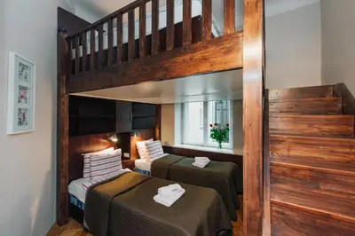 two beds in a room with a staircase at Rembrandt Aparthotel in Kraków