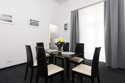 a black dining room table with chairs and a vase of flowers at Rembrandt Aparthotel in Kraków