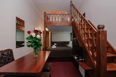 a room with a staircase with a vase of roses on a table at Rembrandt Aparthotel in Kraków