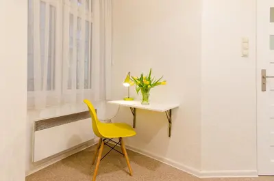 a yellow chair and a table in a room with a window at Central Krak Apartments - studios in Kraków