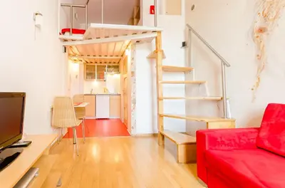 a living room with a red couch and a loft bed at Central Krak Apartments - studios in Kraków