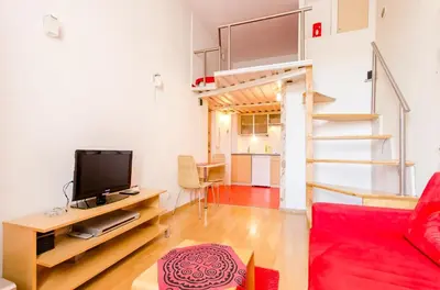 a living room with a couch and a tv and a staircase at Central Krak Apartments - studios in Kraków