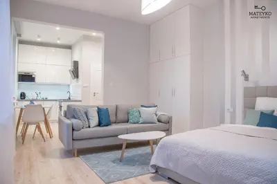 a room with a bed and a couch and a kitchen at Mateyko Apartment in Kraków