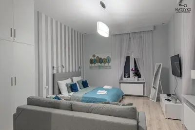 a white bedroom with a bed and a couch at Mateyko Apartment in Kraków