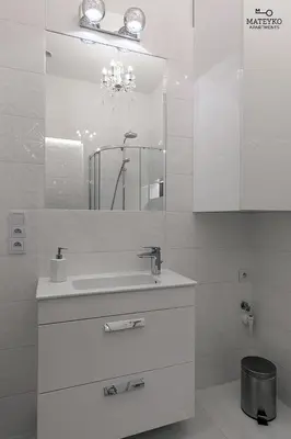 a white bathroom with a sink and a mirror at Mateyko Apartment in Kraków