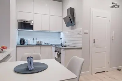 a white kitchen with a table with a hat on it at Mateyko Apartment in Kraków