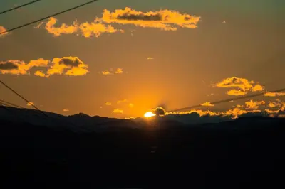 a sunset with the sun setting behind the mountains at Agroturystyka Nad Jeziorem-Osada Indiańska in Czchów
