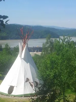 a white tent sitting in the grass near a river at Agroturystyka Nad Jeziorem-Osada Indiańska in Czchów