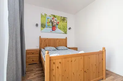 a bedroom with a wooden bed and a painting on the wall at Landmark Apartments in Kraków