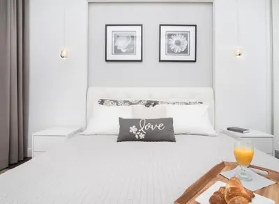 a white bed with a tray of bread and a glass of orange juice at Landmark Apartments in Kraków