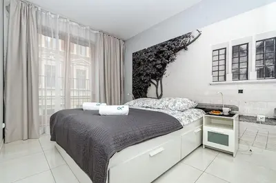 a white bedroom with a bed and a large window at Landmark Apartments in Kraków