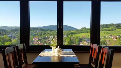 a dining room with a table with chairs and a view at Willa Ostoja in Rabka
