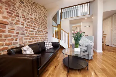 a living room with a leather couch and a brick wall at Gołębia 8 Residence in Kraków