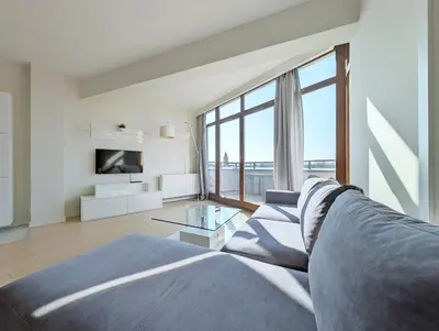 a living room with a couch and a large window at Turnau City Aparthotel in Kraków