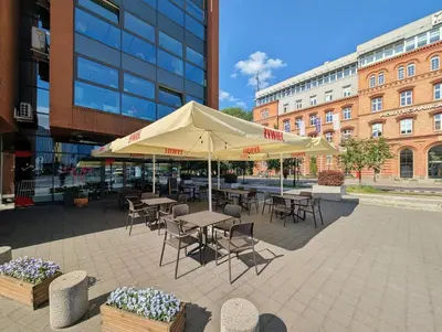 a patio with tables and chairs under aige umbrella at Turnau City Aparthotel in Kraków