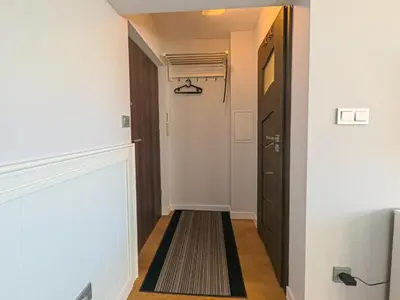 a hallway with a black door and a rug at Apartament Parkowy Rabka in Rabka