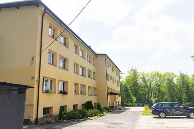 a car parked in front of a yellow building at Apartament Parkowy Rabka in Rabka