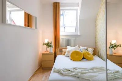 a bedroom with a bed with yellow pillows and a mirror at Kazimierz Apartment in Kraków