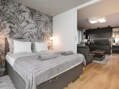 a bedroom with a large bed and a living room at Jacuzzi Apartments in Kraków