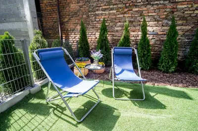 two blue chairs sitting on the grass in a yard at Jacuzzi Apartments in Kraków