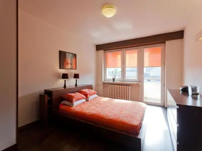 a bedroom with a bed with red pillows and a window at Irish Apartment in Kraków